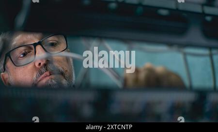 Male system administrator connects cables with server rack working in server room. Maintenance of local area network or web servers. Operation of information systems and networks. Data storage center. Stock Photo