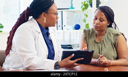 Doctor Consulting With Patient Using Digital Tablet in Medical Office Environment for Health Evaluation Stock Photo