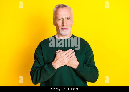 Photo portrait of handsome retired man hands touch chest heart health wear trendy green outfit isolated on yellow color background Stock Photo