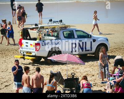 A Red Flag beach safety shutdown for thousands of visitors. RNLI Lifeguards take an unpopular but necessary action by advising swimmers and surfers to vacate the water. Although the popular beach famous for being the home of British surfing is thronged from end to end with record crowd numbers, a decision in light of big, rough, wave conditions combined with an outgoing tide resulted in the Red flags being hoisted to avoid folk getting into difficulties.  A number of major beach safety rescues have taken place in the resort in previous days, including 200 people being evacuated from Whipsiderr Stock Photo