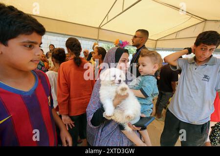 Children pet dogs during a volunteer entertainment initiative for people with disabilities at a camp for displaced Palestinians Children pet dogs during a volunteer entertainment initiative for people with disabilities at a camp for displaced Palestinians in Deir el-Balah in the central Gaza Strip on August 14, 2024 amid the ongoing conflict between Israel and the Palestinian Hamas movement. Photo by Naaman Omar apaimages Deir el-Balah Gaza Strip Palestinian Territory 140824 Dair El Balah NAA 0041 Copyright: xapaimagesxNaamanxOmarxxxapaimagesx Stock Photo