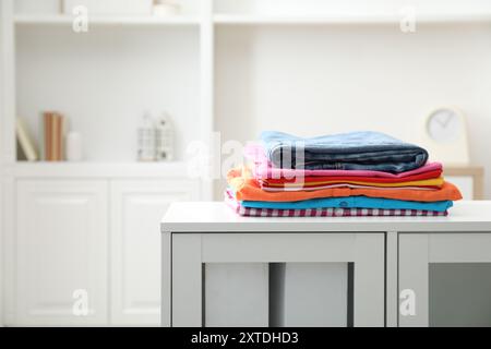 Stack of clean clothes on white dresser indoors Stock Photo