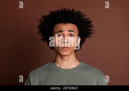 Portrait photo of youth upset guy offended by society with curly haircut wearing gray t shirt isolated on brown color background Stock Photo