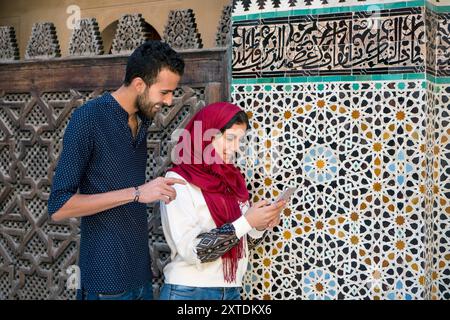 Smiling muslim couple looking at cellphone Stock Photo