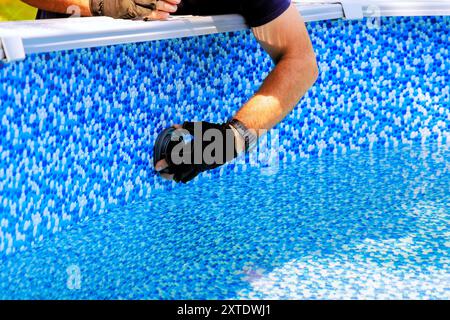 Worker installing water filtration system chlorination in swimming pool frame Stock Photo