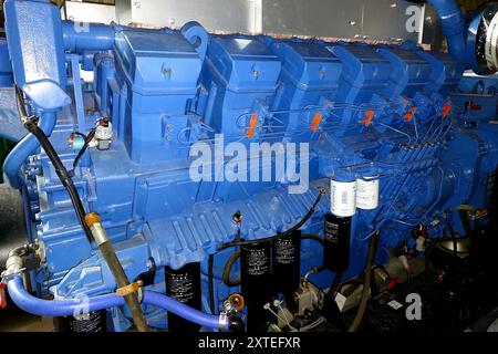 This large diesel engine powers an electric generator, showcasing its components and connections within an industrial setting. Stock Photo