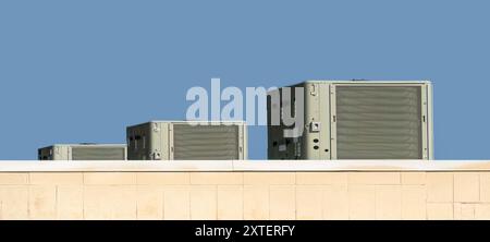 Horizontal shot of three commercial air conditioning units on the roof of a grocery store. Stock Photo