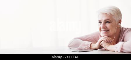 Dreamy senior lady listening to music, using phone Stock Photo