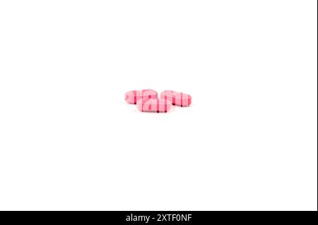 Concept grouping of small pink colored capsules on white background Stock Photo