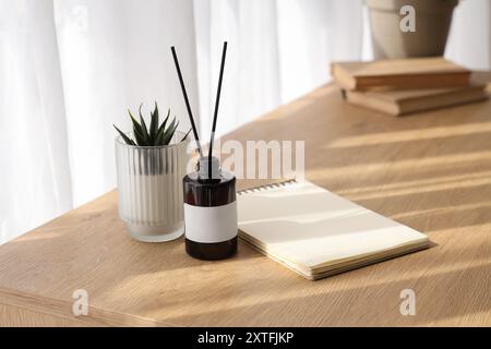 Aroma diffuser, houseplant and notepad on table in room Stock Photo