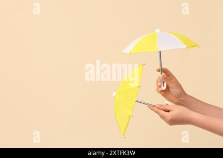 Female hands with different mini umbrellas on beige background Stock Photo