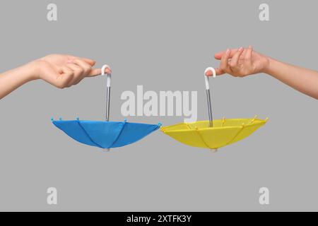 Female hands with different mini umbrellas on grey background Stock Photo