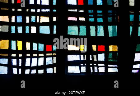 Abstract stained glass window with colorful rectangular and square patterns in shades of blue, red, green, yellow, and black. Stock Photo