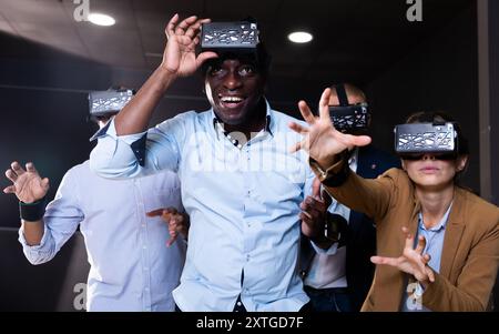Cheerful nice friends playing video games using virtual reality glasses Stock Photo