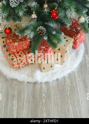 Merry Christmas and happy new year background. Top view of many pattern of gift boxes decorations under green Christmas tree on white carpet and wood Stock Photo