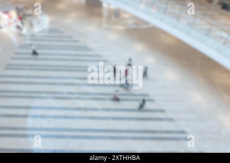 A blurry image of a shopping mall in Shenzhen, China, with people walking on the floor and blurred bokeh lights. Stock Photo