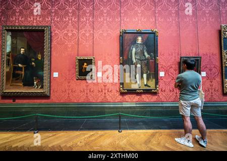 A young male looking at a portrait, painting on a wall inside the National Gallery in London, England. London National Gallery art museum interior. Stock Photo