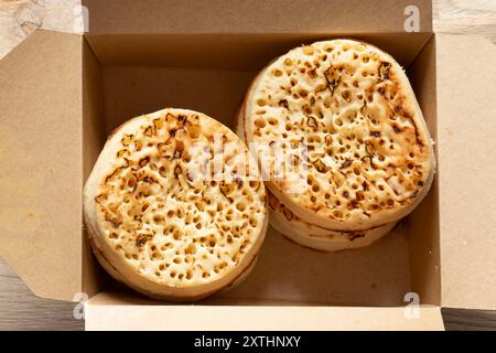 Crumpets in a cardboard tray, fresh from a bakery. Biodegradable plastic free eco friendly packaging. Stock Photo