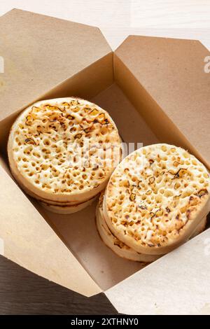 Crumpets in a cardboard tray, fresh from a bakery. Biodegradable plastic free eco friendly packaging. Stock Photo