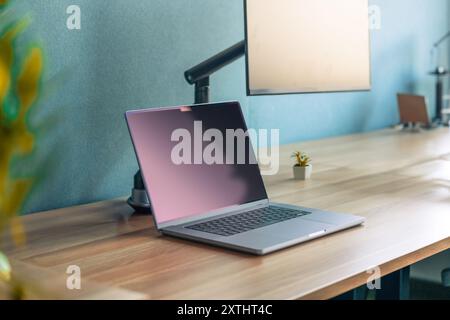 Office interior. Laptop standing on table next to monitor. Clean empty screen. Stock Photo