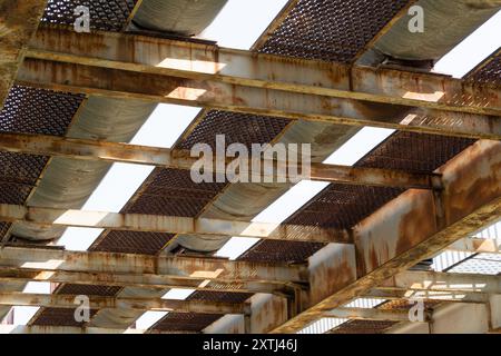 Rusty steel beams and metal grates under an industrial structure. Under the bridge. Stock Photo