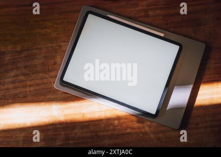Graphic tablet notebook empty blank screen mockup wooden table surface. Close laptop sun light. Stock Photo