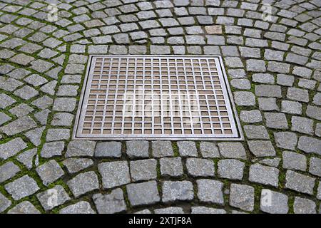 Paving stones background with metal manhole plate Stock Photo