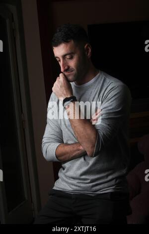 portrait of a young latino man deep in thoughts in low lighting Stock Photo