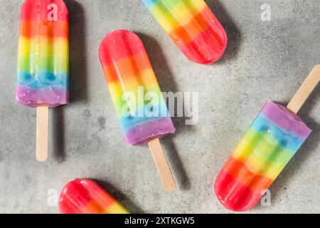 Sweet Summer Rainbow Popsicles with Different Fruit Flavours, laying on grey table background Stock Photo