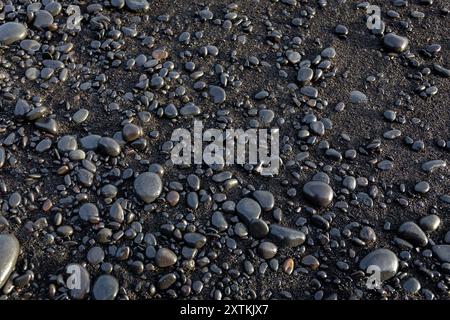 Shiny basalt stones background on black sand, Reynisfjara Black Sand Beach, Iceland, top view. Stock Photo