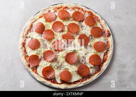 An uncooked fresh homemade three cheese pepperoni pizza, with Mozzarella, Parmesan and Gorgonzola. Stock Photo