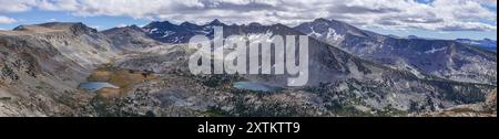 A mountain range with a lake in the foreground. The mountains are covered in snow and the lake is surrounded by trees. The scene is peaceful and seren Stock Photo
