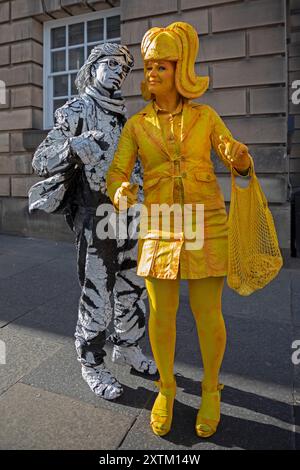 Edinburgh Festival Fringe, Royal Mile, Edinburgh, Scotland UK. 15 August 2024. Lemon Lush (Isabella) meets Estevanmortenson the monochromatic bicycle man on the High Street, the professional street statues often have adjacent pitches on the Royal Mile but they decided to have a few minutes together on this bright Thursday evening. Credit: Arch White/alamy live news. Stock Photo