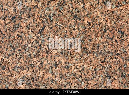 Red granite texture. Magma, mosaic backdrop. A variegated, spotted background of red (brown) granite. The stone granite surface of dark-red color. Stock Photo