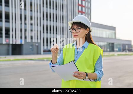 Industrial worker female builder with working documents, outdoor construction Stock Photo