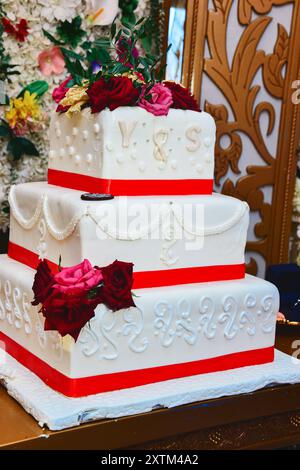 Three-tiered wedding cake with a red ribbon Stock Photo