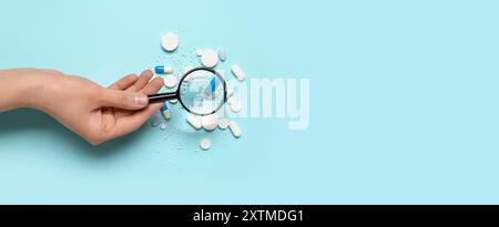 Female hand with magnifier and pills on blue background with space for text Stock Photo