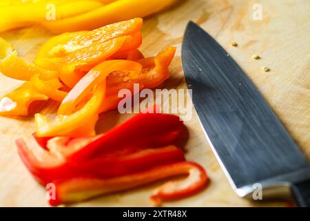 Sliced bell peppers on wooden cutting board with knife Stock Photo