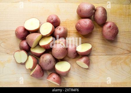 Closeup of sliced red potatoes on wooden cutting board with natural light Stock Photo