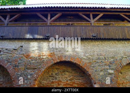 View from below of the brick defensive wall with arches and a battlement built between the Carpenters' Tower and the Potters' Tower in Sibiu Stock Photo