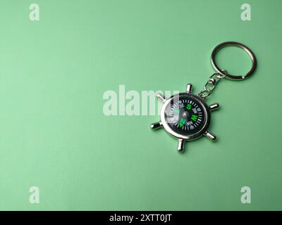 Compass keychain on a green background with copy space and text. Holiday and travel concept. Stock Photo