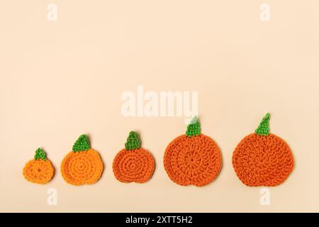 Pattern of knitted orange pumpkins from small to large on a beige background. Concept of harvest, Thanksgiving, Halloween. Flat lay, top view, copy space Stock Photo