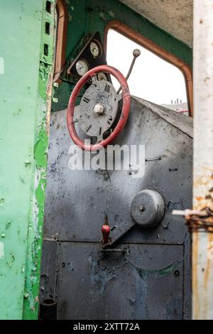 Detailed view of an old, rusty steam train cabin with vintage controls and gauges at a historical railway site during daylight Stock Photo