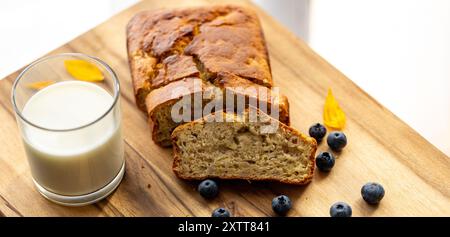 glass of milk and sweet homemade banana bread with crispy crust on a wooden board, cooking at home Stock Photo