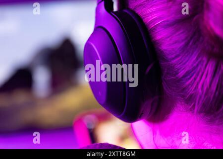 woman software developer in modern wireless headphones against laptop screen with software code, neon light, for software development ,education topic Stock Photo