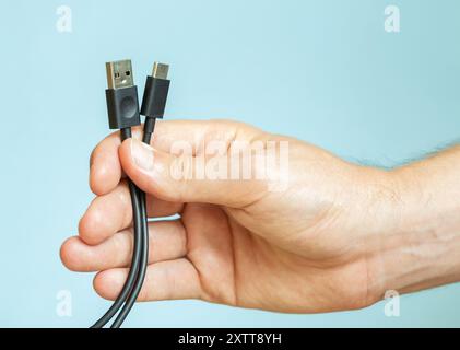 man holds several cables in hand, different types of USB cables, technology and connection concept Stock Photo