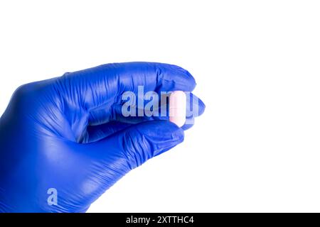 Hand in blue glove holding a pink pill isolated on white background. clipping path Stock Photo