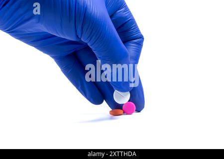Hand in blue glove holding a pill isolated on white background with clipping path Stock Photo