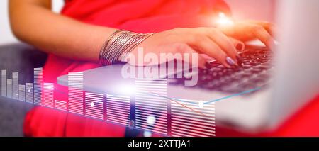 A woman is typing on a laptop with a city skyline in the background Stock Photo