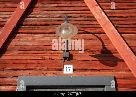 old lamp on red wooden log wall exterior Stock Photo